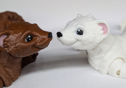 Two 3d printed ferret fidget toys nose to nose with each other. one is a shiny brown and the other is a soft white on a plain white background