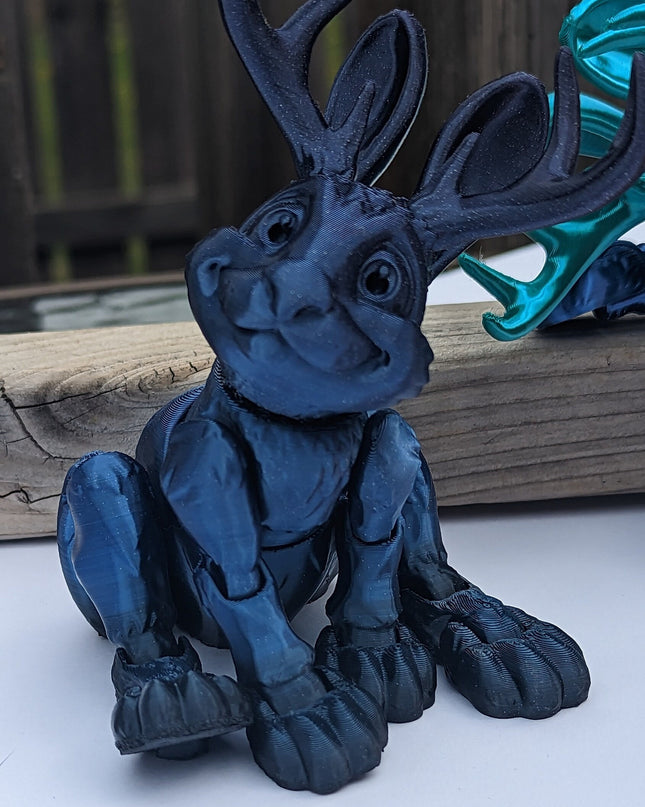 Blue fantasy folklore jackalope  figurine on a white surface with a blurred background