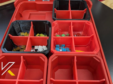 Red storage bins with compartments containing small items on a black surface.
