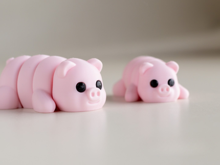 Two pink pig figurines on a light surface with a neutral background