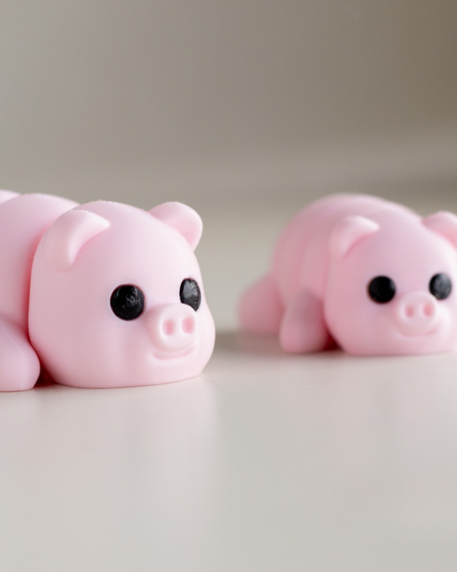 Two pink pig figurines on a light surface with a neutral background