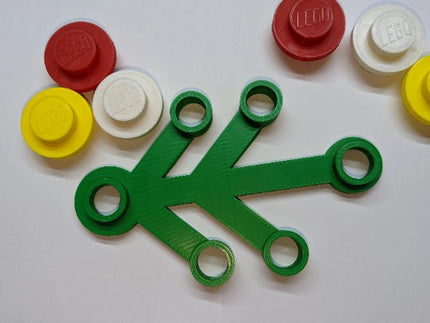 Green plastic piece with circular holes on a white background with brand pieces.