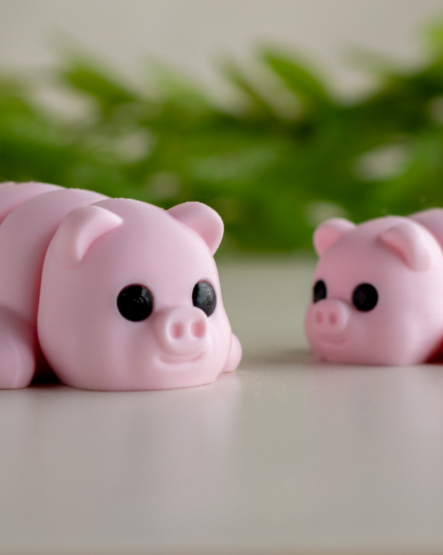 Two pink pig-shaped squishies on a light surface with greenery in the background