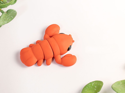 Orange lobster-shaped toy on a light background with green leaves