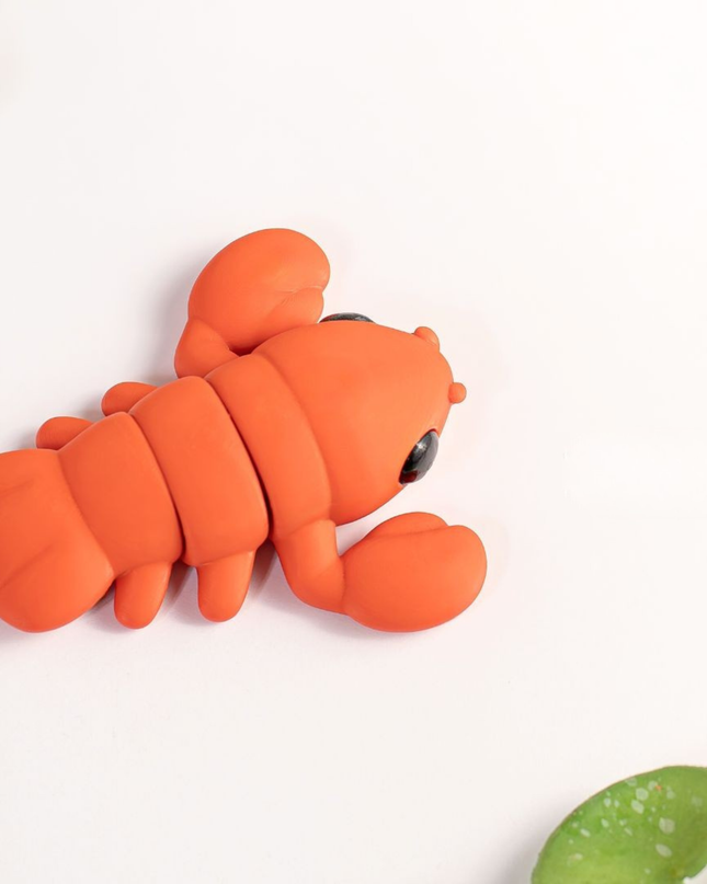 Orange lobster-shaped toy on a light background with green leaves