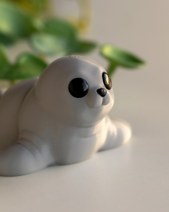 Toy seal figurine on a light surface with green leaves in the background
