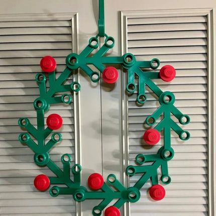 Green plastic wreath with red berries on a white door