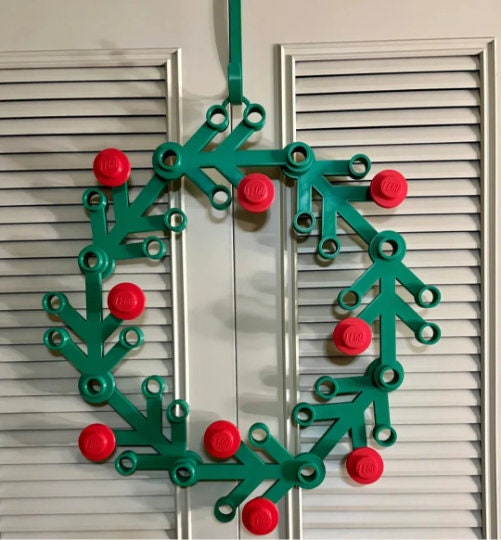 Green plastic wreath with red berries on a white door