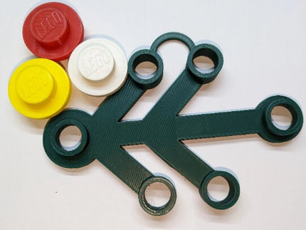 Green tool with circular components and colorful plastic pieces on a white background