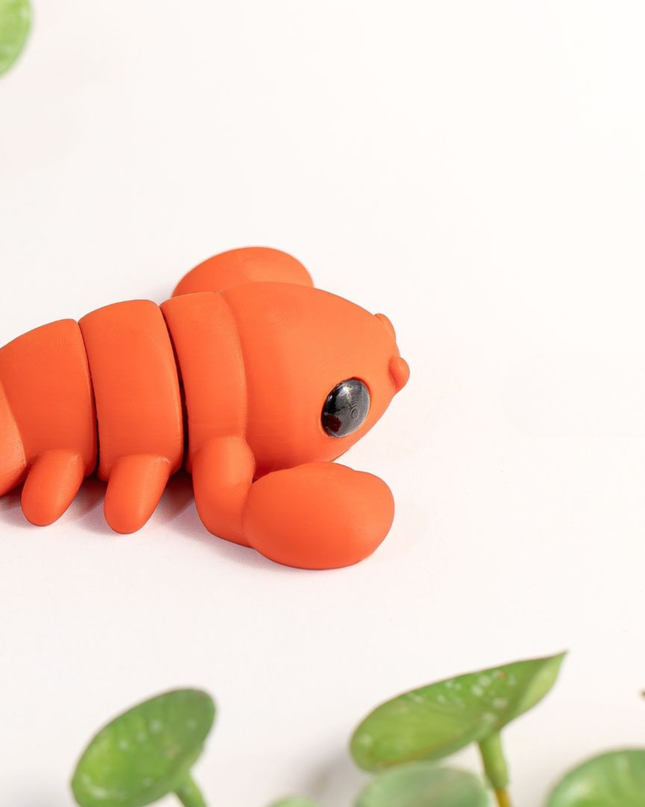 Orange Lobster toy with green leaves on a white background
