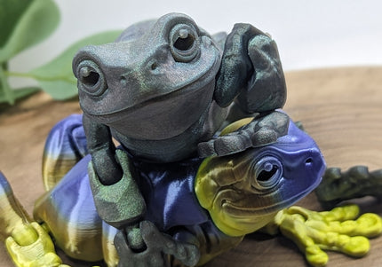 Colorful frog figurine on a wooden surface with a plant in the background