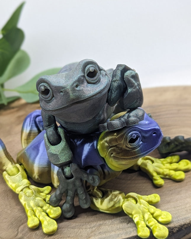 Colorful frog figurine on a wooden surface with a plant in the background
