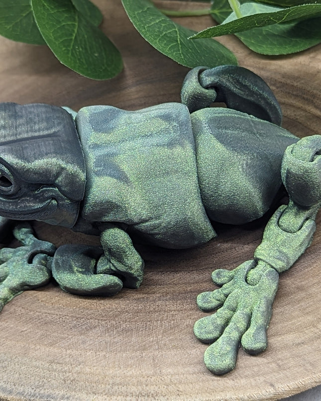 Green frog sculpture on a wooden surface with leaves in the background