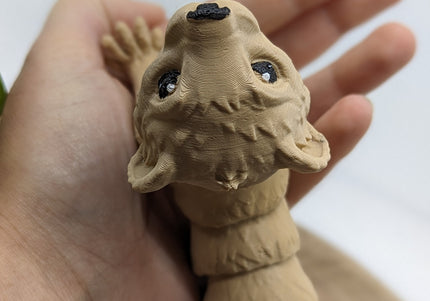 Hand holding a 3d printed ferret toy  with black eyes against a white background