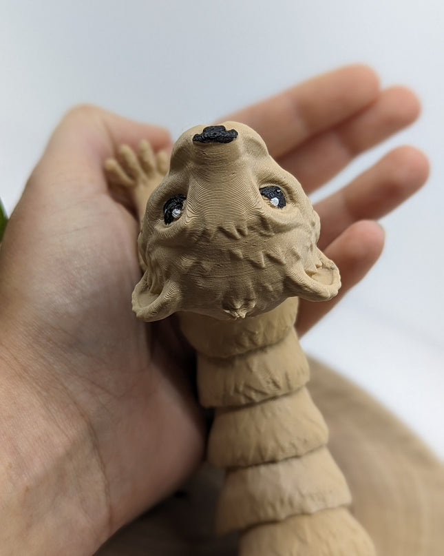 Hand holding a 3d printed ferret toy  with black eyes against a white background