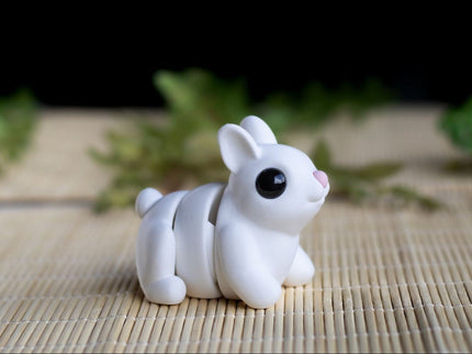 White ceramic rabbit figurine on a woven mat with blurred greenery in the background