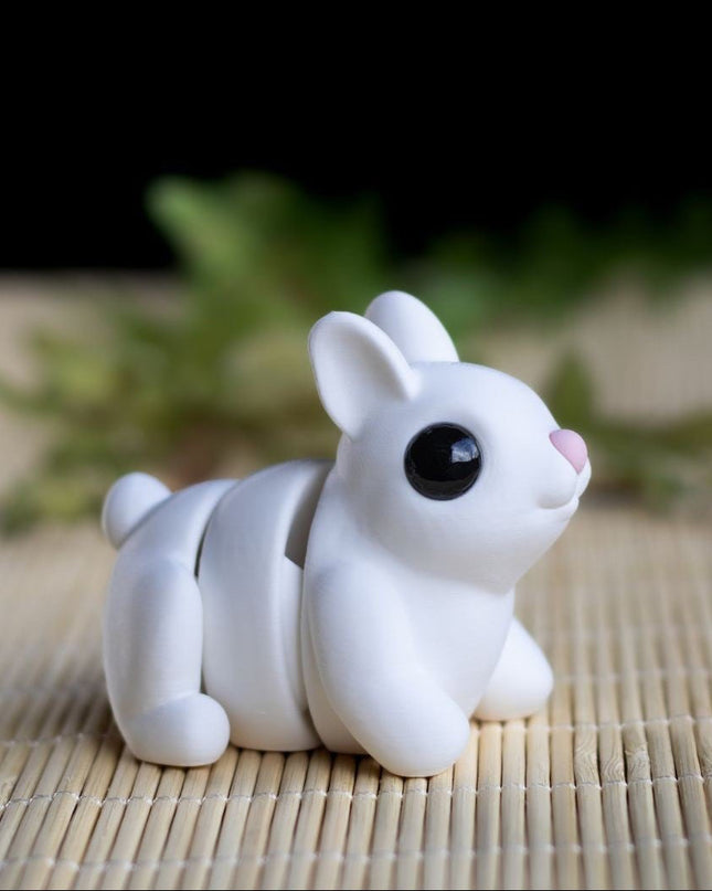 White ceramic rabbit figurine on a woven mat with blurred greenery in the background
