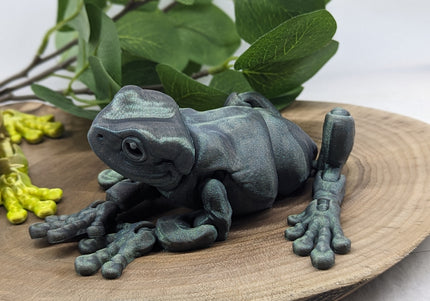 Decorative frog sculpture on a wooden surface with green leaves in the background