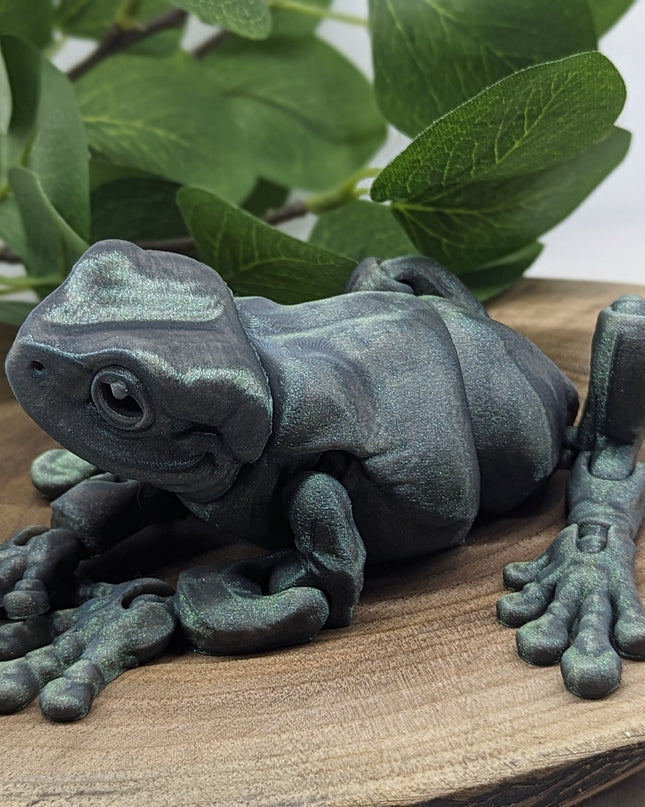 Decorative frog sculpture on a wooden surface with green leaves in the background