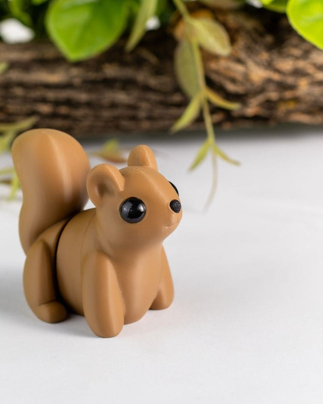 Small brown squirrel figurine on a white surface with greenery in the background