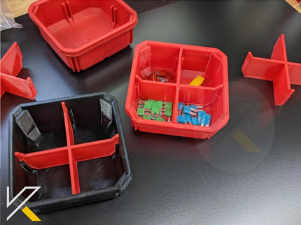 Red and black plastic trays on a dark surface with small items inside