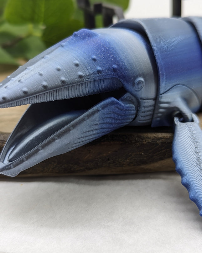 3d printed Blue and gray textured humpback whale head on a wooden surface.