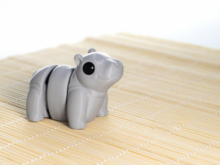 Gray hippo articulating toy shaped on a bamboo mat with a white background
