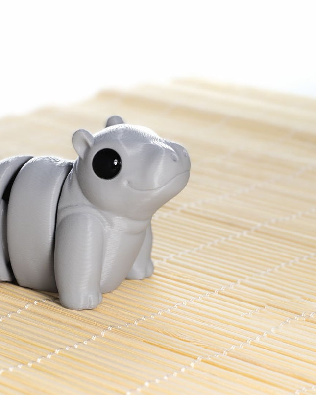 Gray hippo articulating toy shaped on a bamboo mat with a white background