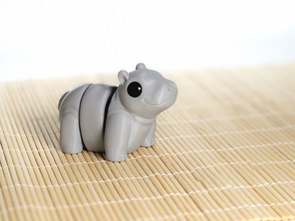 Gray hippo articulating toy shaped on a bamboo mat with a white background