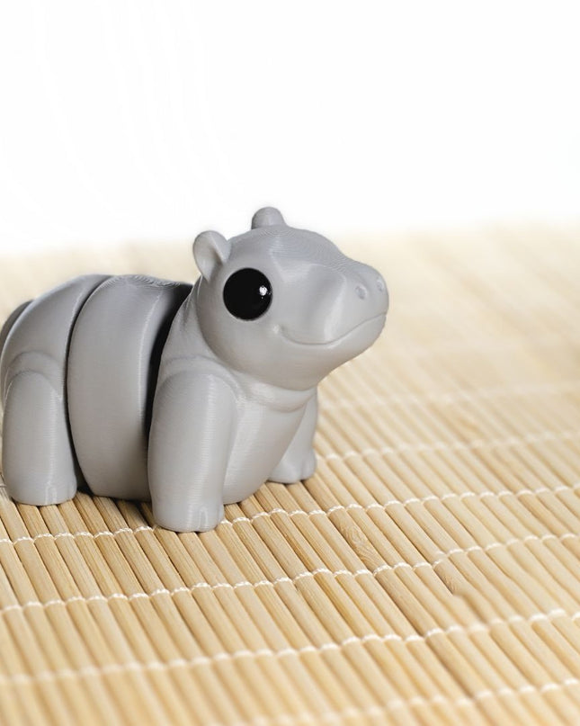 Gray hippo articulating toy shaped on a bamboo mat with a white background