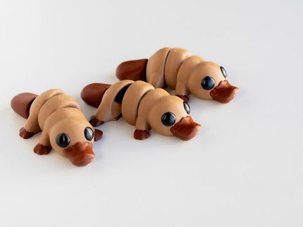 3 platypus articulating toys with a light brown body and dark brown bill and feet, on a white background