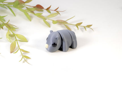 Gray rhino figurine on a white background with green leaves
