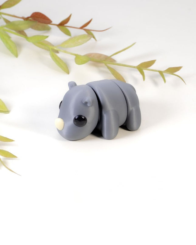 Gray rhino figurine on a white background with green leaves