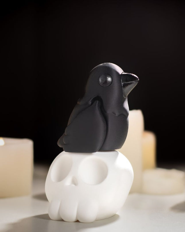 Black raven toy sitting on a cartoon white skull with lit candles in the background