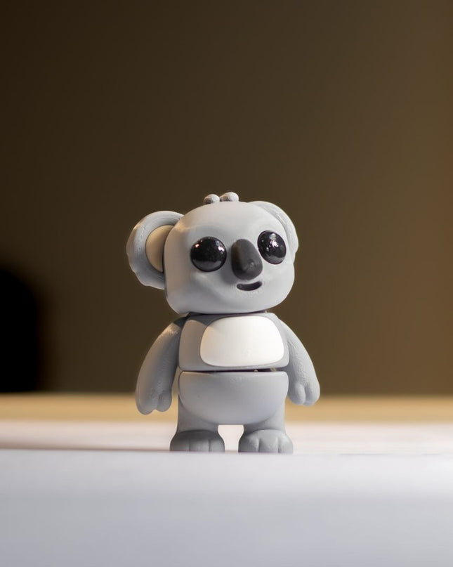 Small gray koala toy on a reflective surface with a blurred background