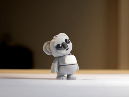 Small gray koala toy on a light surface with a blurred background