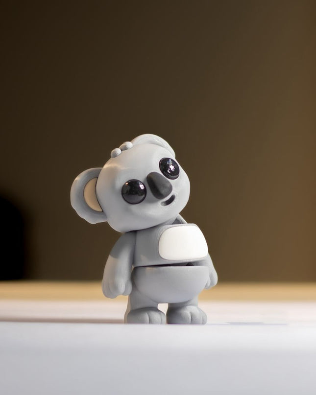 Small gray koala toy on a light surface with a blurred background