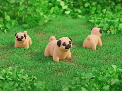 Three pug-shaped toys on a grassy field with green foliage.