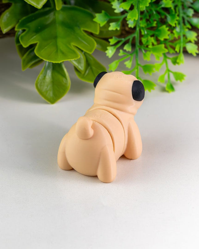 Small beige dog figurine on a white surface with green leaves in the background