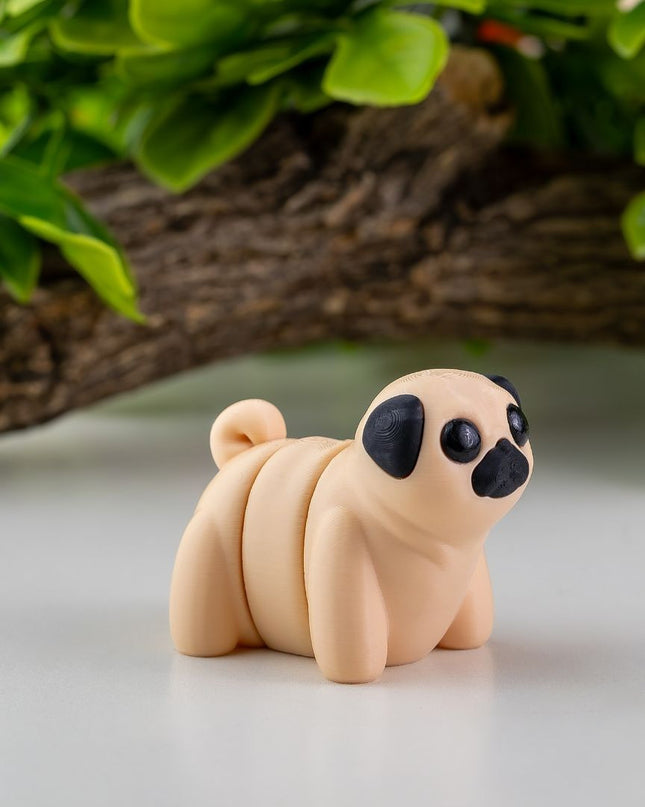 Small toy Pug on a white surface with green leaves in the background