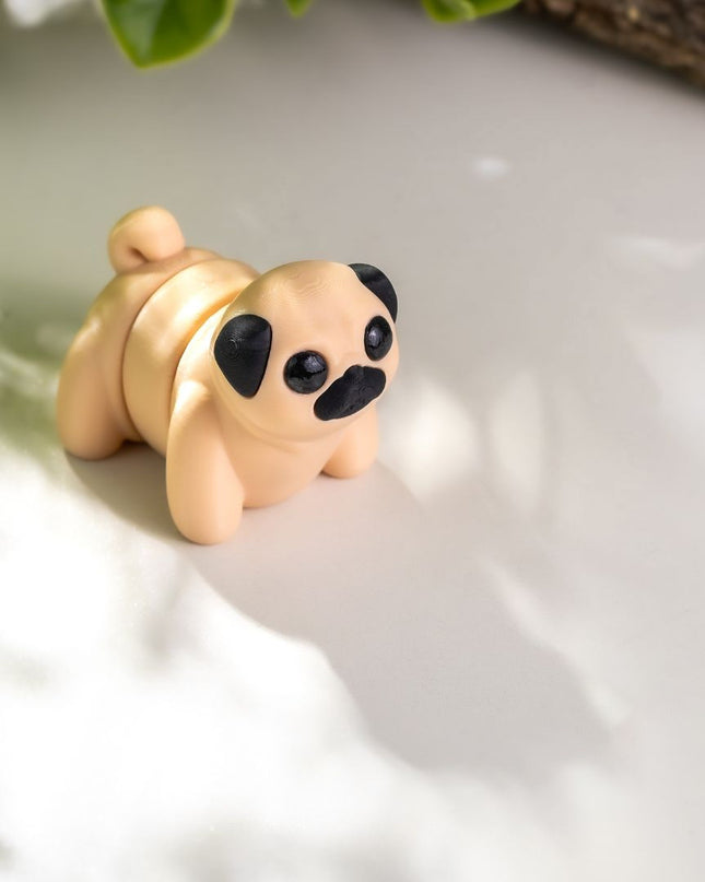 Small toy Pug dog figurine on a textured surface with greenery