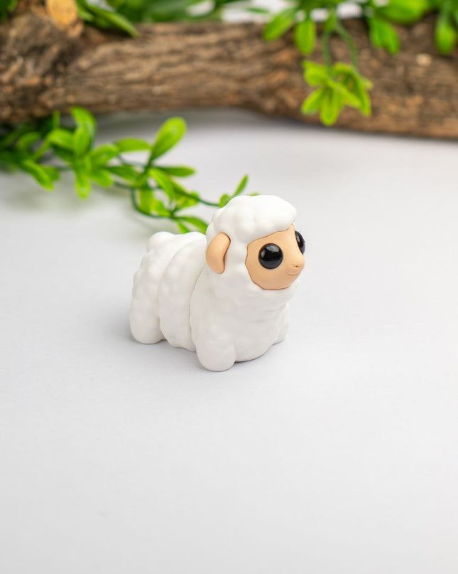Small white figurine of a sheep on a light surface with greenery in the background